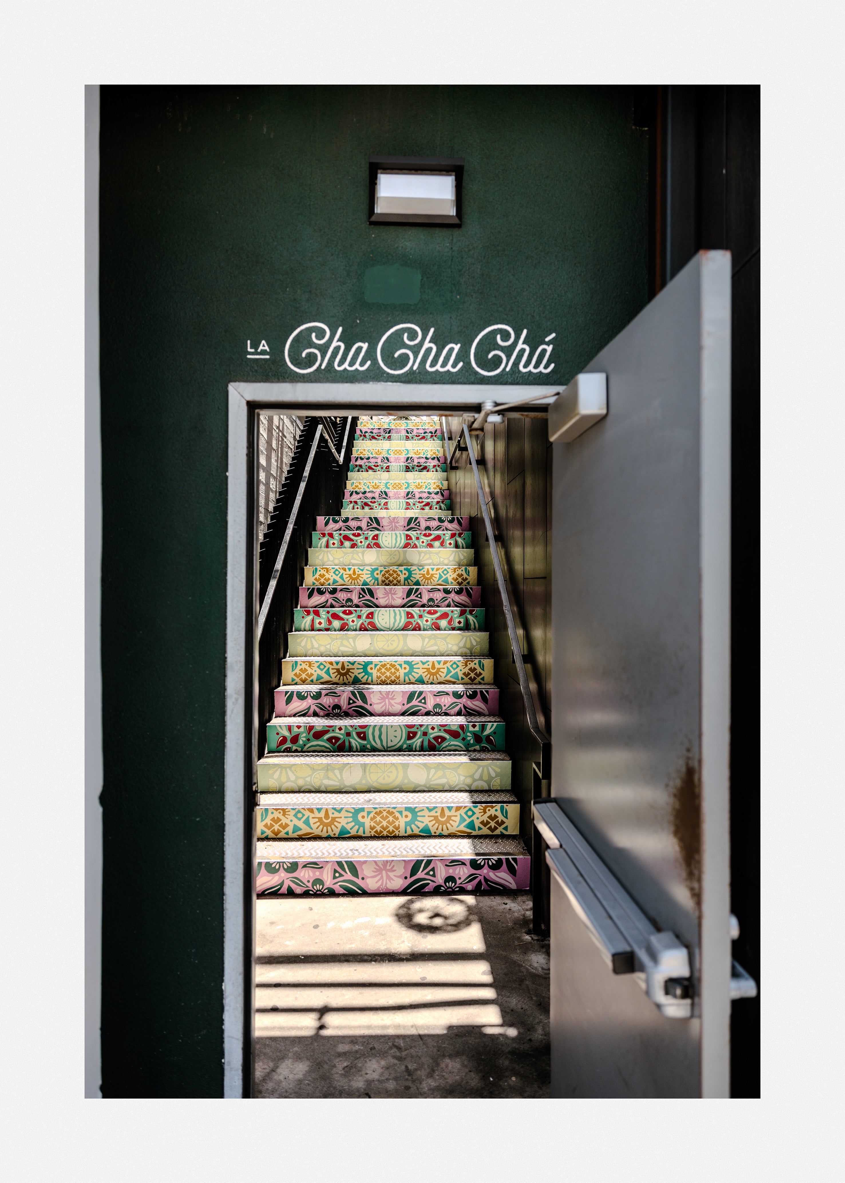 Vibrant pattern on a staircase behind an open door leading into a cafe.