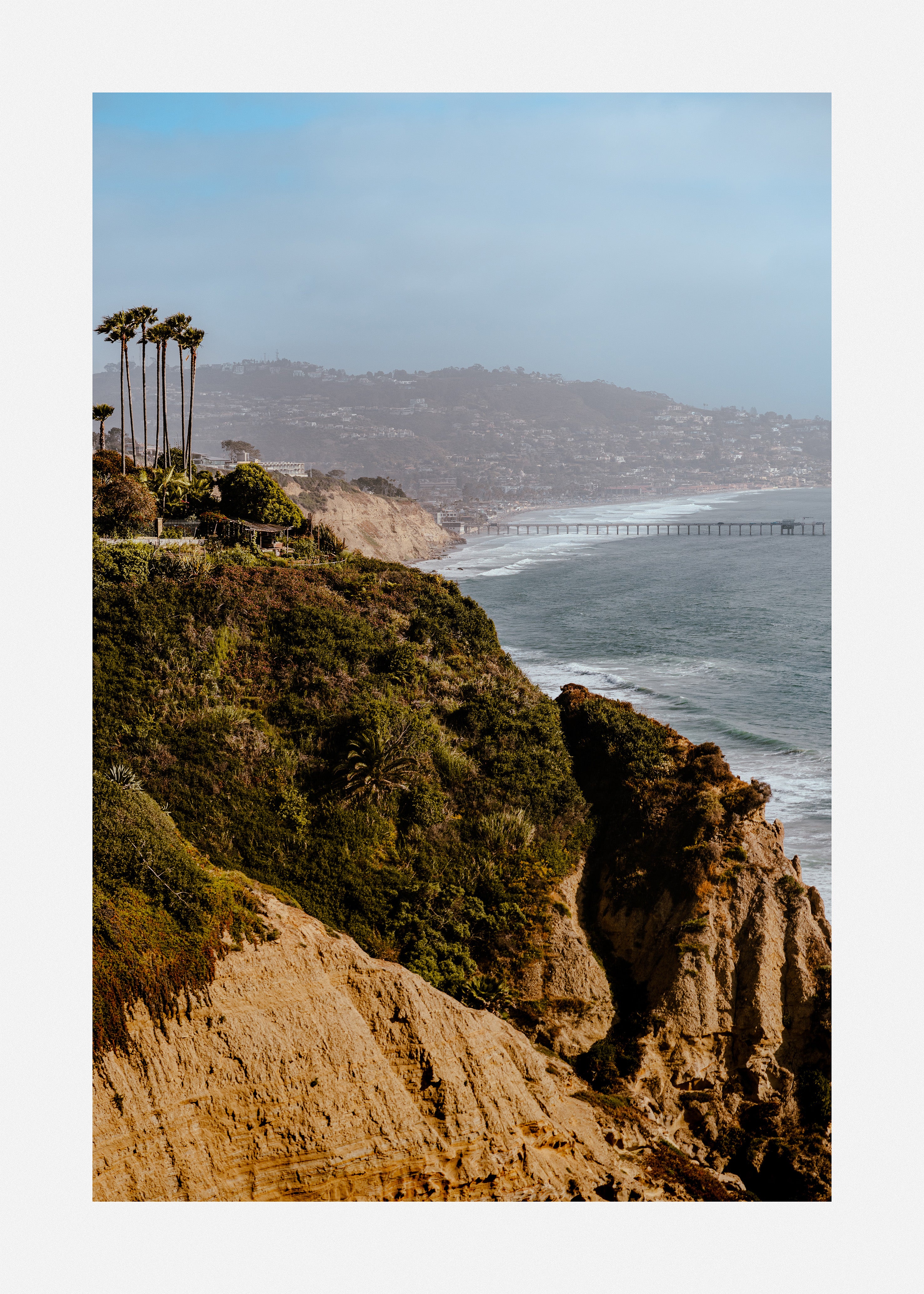 Art print of a wooden pier stretching into the pacific ocean from a rocky coast.