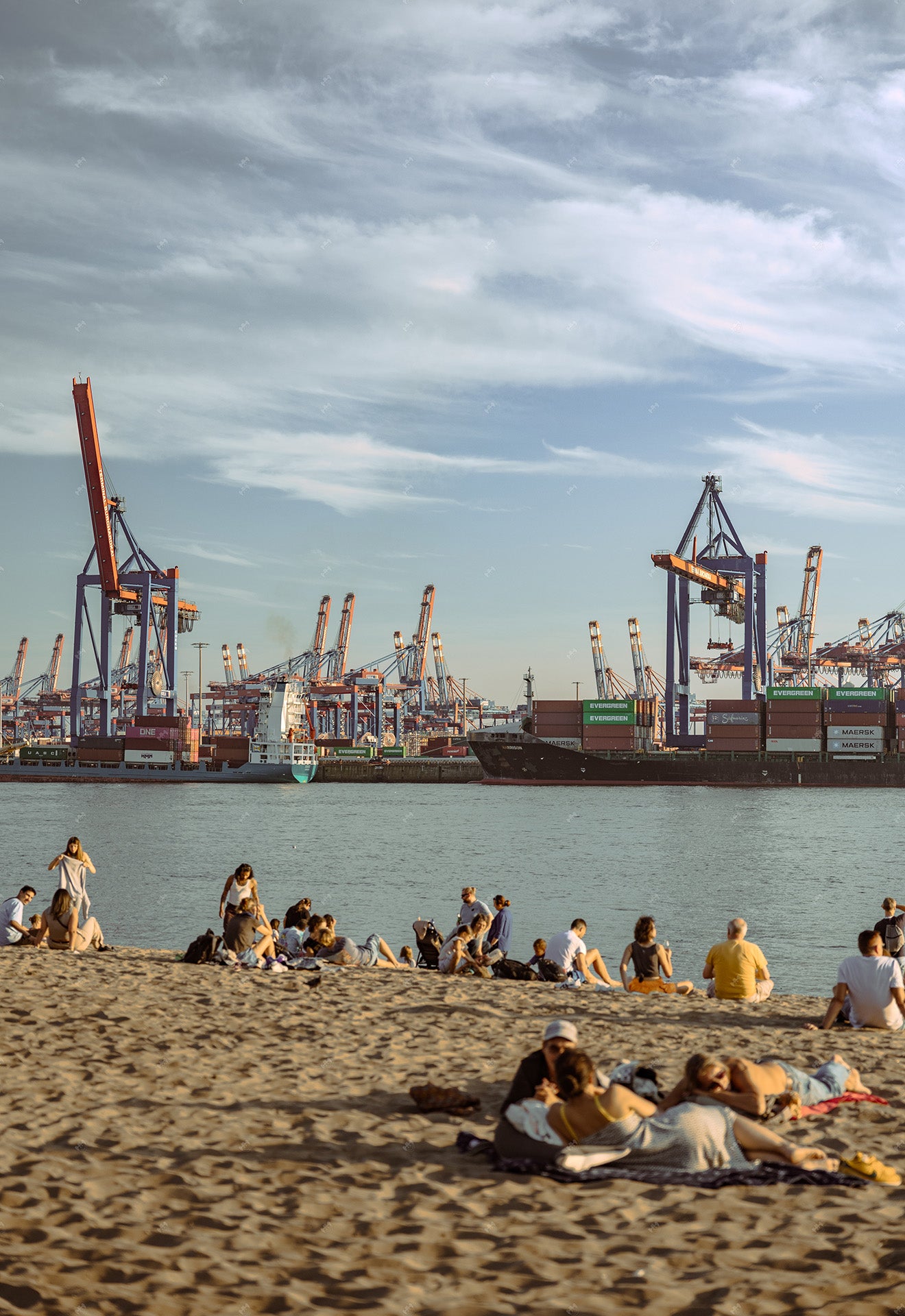 Beach in Hamburg with harbor structures in the background.
