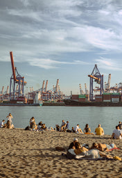 Beach in Hamburg with harbor structures in the background.